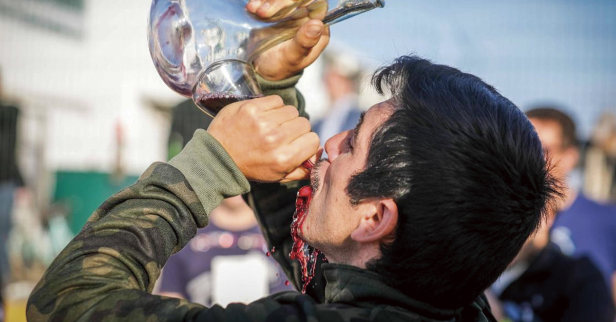 hombre bebiendo de un porron de vino